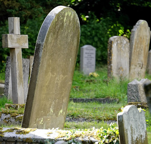 A view of a cemetery with gravestones and trees in the background.